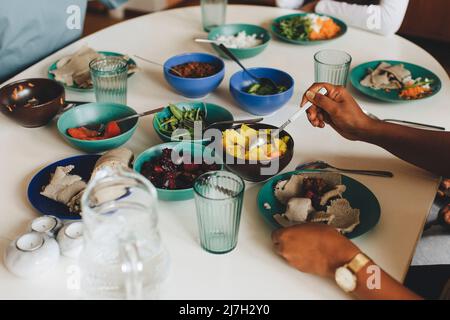 Mani di donna che prendono il cibo dalla ciotola durante il pranzo a casa Foto Stock