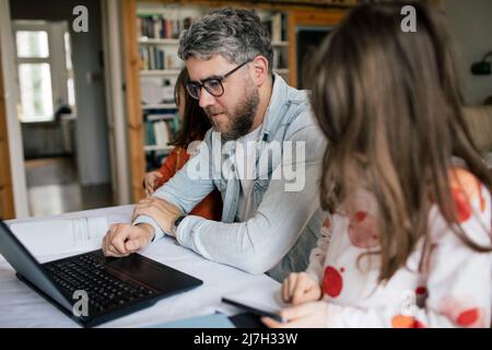 Uomo adulto medio che usa il computer portatile delle figlie a casa Foto Stock