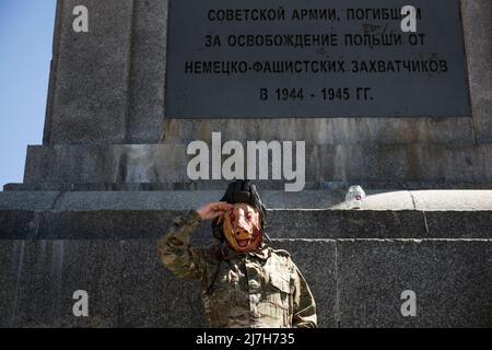 Varsavia, Polonia. 09th maggio 2022. Un uomo vestito da soldato sovietico con una maschera di maiale sul viso saluta mentre si erge sul monumento ai soldati sovietici che sono morti nella seconda guerra mondiale Centinaia di ucraini e attivisti polacchi hanno protestato in un cimitero di Varsavia contro i soldati dell'Armata Rossa che sono morti durante la seconda guerra mondiale L'ambasciatore russo in Polonia, Sergey Andreev, è stato colpito con vernice rossa da manifestanti contrari alla guerra in Ucraina in un evento annuale della Giornata della Vittoria che commemorava la fine della seconda guerra mondiale L'ambasciatore Sergey Andreev arrivò al cimitero dei soldati sovietici per deporre i fiori il giorno della Vittoria, ma il diploma Foto Stock