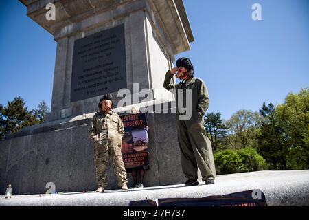 Varsavia, Polonia. 09th maggio 2022. Un uomo vestito da soldato sovietico con una maschera di maiale sul viso saluta mentre si erge sul monumento ai soldati sovietici che sono morti nella seconda guerra mondiale Centinaia di ucraini e attivisti polacchi hanno protestato in un cimitero di Varsavia contro i soldati dell'Armata Rossa che sono morti durante la seconda guerra mondiale L'ambasciatore russo in Polonia, Sergey Andreev, è stato colpito con vernice rossa da manifestanti contrari alla guerra in Ucraina in un evento annuale della Giornata della Vittoria che commemorava la fine della seconda guerra mondiale L'ambasciatore Sergey Andreev arrivò al cimitero dei soldati sovietici per deporre i fiori il giorno della Vittoria, ma il diploma Foto Stock