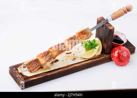 Salmone alla griglia su spiedini di acciaio inossidabile, servito su pane piatto con salsa di limone e Pomegrenate. Isolato su sfondo bianco. Foto Stock