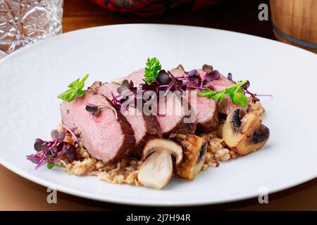 Carne di cervo a fette servita in cima al Risotto ai funghi. Foto Stock