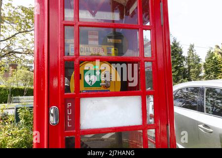 Uso intelligente di una vecchia e iconica cassetta telefonica britannica - (Walton on on the Hill, Surrey, Regno Unito) gli abitanti del villaggio hanno installato un defibrillatore all'interno per l'accesso immediato da parte di residenti e visitatori. Foto Stock