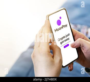 Londra, UK, marzo 2022: Una giovane donna irriconoscibile che naviga sul sito MoonPay con un telefono in soggiorno durante il giorno. Valuta Crypto, Financ Foto Stock