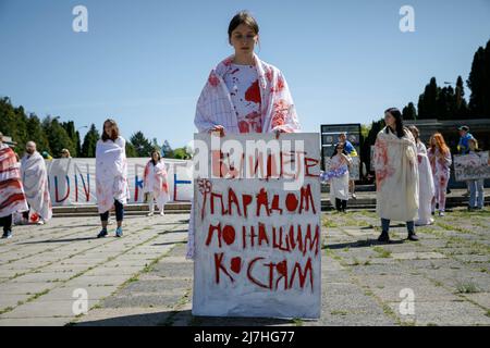 Varsavia, Polonia. 09th maggio 2022. La donna tiene un cartello durante lo spettacolo al cimitero dei soldati sovietici di Varsavia il giorno della Vittoria. Nel 77th anniversario della vittoria dell'Armata Rossa sulla Germania nazista, gli attivisti ucraini si sono esibiti al cimitero dei soldati sovietici di Varsavia, protestando contro l'invasione russa dell'Ucraina. Gli attivisti hanno vietato alla delegazione russa guidata da Sergey Andreev, ambasciatore della Federazione Russa in Polonia, di entrare nel cimitero. Durante questo tentativo i diplomatici sono stati spenti di sangue dagli attivisti ucraini. Foto Stock