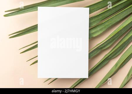 Mockup carta di invito bianco con una palma su un tavolo beige. Formato 5x7, A6, A5 volantini Foto Stock