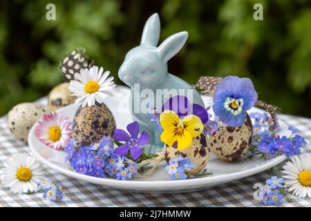 decorazione pasquale con fiori primaverili in uova di quaglia e coniglietto pasquale Foto Stock