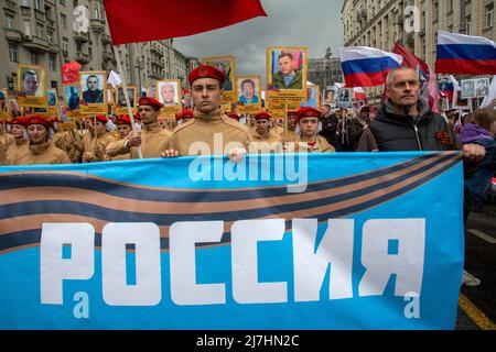 Mosca, Russia. 9th maggio 2022. La gente ha ritratti di persone che sono morte a Donbass nel 2014-2022 e una bandiera con l'iscrizione 'Russia', durante la marcia del reggimento immortale che segna il 77th anniversario della vittoria nella seconda guerra mondiale in via Tverskaya nel centro di Mosca, Russia. Nikolay Vinokurov/Alamy Live News Foto Stock