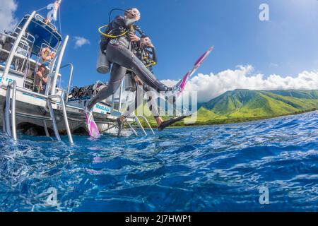 Divers (MR) scendere una barca di immersione nell'Oceano Pacifico fuori da Ukumehame, Maui, Hawaii. Foto Stock