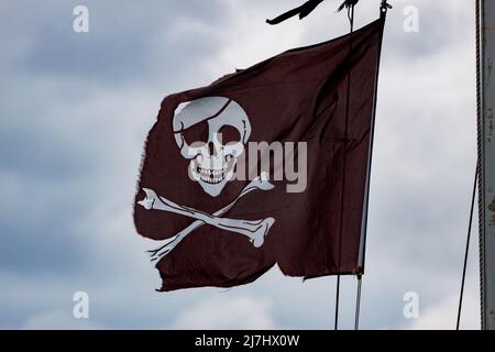 Una bandiera pirata con teschio e ossa intemperie e usurate. Foto Stock