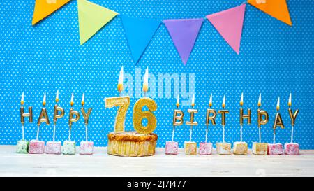 Buon compleanno dalle lettere della candela su sfondo blu con spazio bianco della copia del punto della polka. Buon cupcake di compleanno con candela dorata che brucia Foto Stock