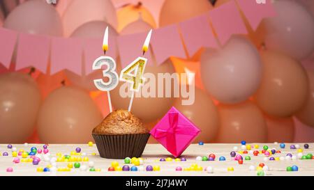 Decorazioni palloncino e una candela di compleanno felice con un numero in una torta. Auguri di buon compleanno in colori rosa per una ragazza, spazio copia. Muffin Foto Stock