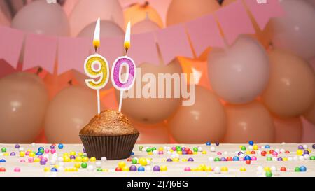 Decorazioni palloncino e una candela di compleanno felice con un numero in una torta. Auguri di buon compleanno in colori rosa per una ragazza, spazio copia. Muffin Foto Stock