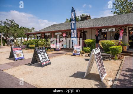 Temecula, CA, USA - 11 aprile 2022: Quartiere della città vecchia. Negozi di antiquariato e articoli da regalo raggruppati in un edificio sotto il cielo blu. Verde fogliame e colorato b Foto Stock