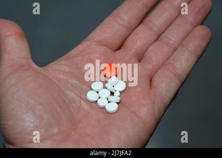 Pillole di tenuta di mano maschile, pillole colorate, farmaci, vitamine in mano dell'uomo, Sanità, coronavirus, trattamento, protezione, concetto di soluzione e medicina, Foto Stock