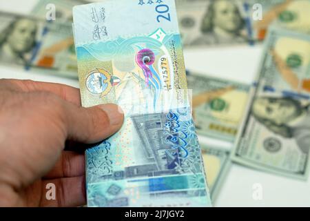 Mano dell'uomo che tiene una pila di 20 venti dinari del Kuwait banconote soldi, spendere, dare ed usare il concetto di soldi, pagare ed acquistare usando le banconote su b Foto Stock