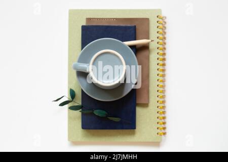 Notebook, tazza da caffè, matita su sfondo bianco. Disposizione piatta, vista dall'alto, spazio per la copia Foto Stock