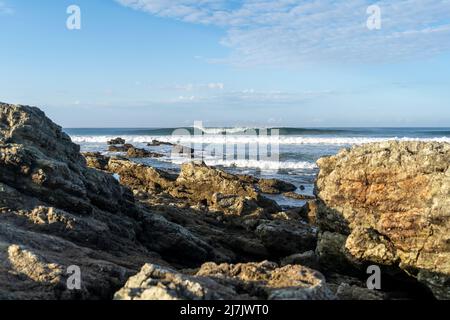 Un'onda perfetta che si infrangono dietro le rocce. Surf in Costa Rica. Foto Stock