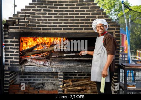 2022.12.03 Province della Repubblica Dominicana la Altagracia. Uno chef maschile del ristorante in un forno a barbecue. Popolo dominicano. Foto Stock