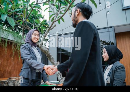 l'uomo d'affari musulmano e le donne che scuotono le mani in ufficio Foto Stock
