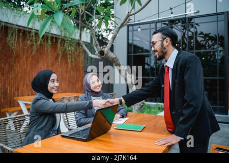 l'uomo d'affari musulmano e le donne che scuotono le mani in ufficio Foto Stock