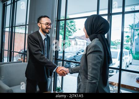 l'uomo d'affari musulmano e le donne che scuotono le mani in ufficio Foto Stock