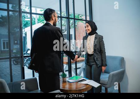 l'uomo d'affari musulmano e le donne che scuotono le mani in ufficio Foto Stock