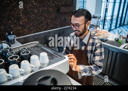 Il barista Happy Male prepara il caffè con una macchina per il caffè Foto Stock