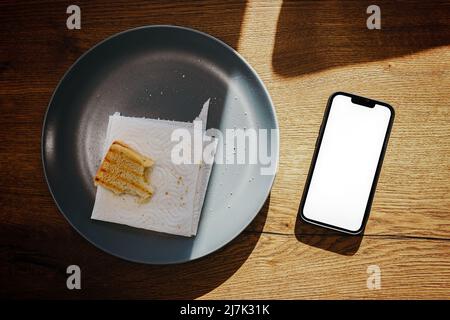 Smartphone e pane tostato sul piatto in cucina, vista dall'alto Foto Stock