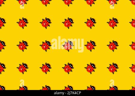 Motivo senza cuciture realizzato con ladybugs su sfondo giallo, come sfondo o texture. Carta da parati estiva luminosa. Vista dall'alto, disposizione piatta. Foto Stock