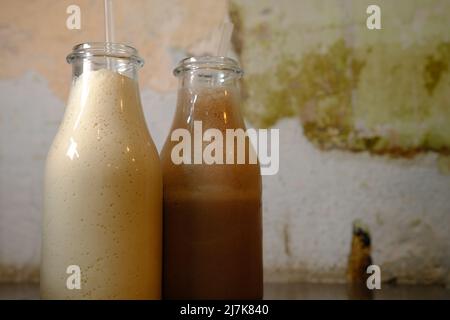 Milkshake latte al cioccolato in bottiglie con paillette vintage sfondo closu vista laterale. Foto Stock