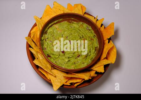 Salsa guacamole messicana e tortilla chips su un isolato sfondo bianco. Ciotola di guacamole con fiches di nachos. Vista dall'alto. Foto Stock