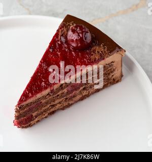 Torta di mousse al cioccolato con ciliegie scure su un piatto bianco. Primo piano. Messa a fuoco selettiva, menu Foto Stock