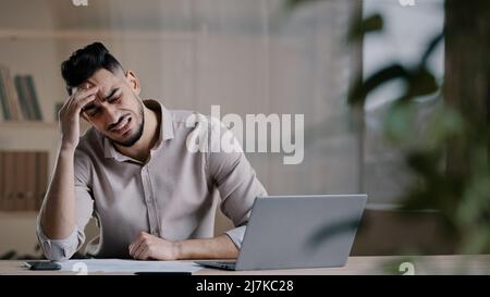 Infelice scioccato arabo maschio lavoratore guardare lo schermo del laptop sensazione nervosa sconvolto con cattive notizie problemi di studio fallimento esame frustrato giovane uomo Foto Stock