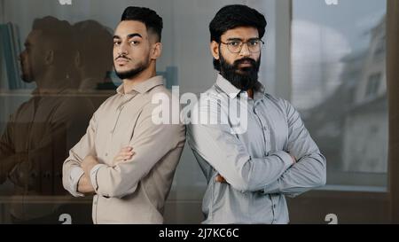 Coppia multirazziale diversi uomini d'affari colleghi colleghi colleghi colleghi maschi colleghi partner arabo barbato uomo in occhiali ispanico giovane ragazzo in piedi al coperto Foto Stock