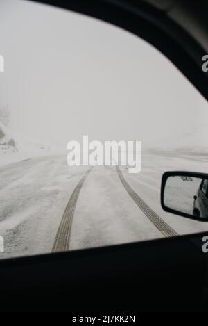 Attraverso la finestra di automobile di strada vuota diritta innevata con tracce coperte di hoarfrost in freddo giorno d'inverno in campagna Foto Stock