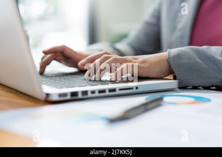 Business analista concetto la donna ufficiale digitando informazioni finanziarie sul computer portatile. Foto Stock