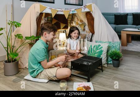 I fratelli si accamparano a casa tostando marshmallows Foto Stock