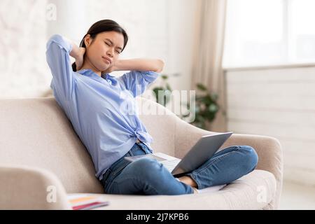 Donna asiatica infelice freelancer strofinare il collo Foto Stock