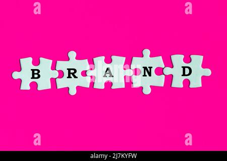 Testo del marchio sul puzzle mancante sullo sfondo della copertina rosa. Concetto di branding Foto Stock