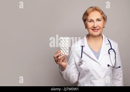 Felice sorridente medico donna anziano mostrando pillole. Medicina e concetto di assistenza sanitaria. Foto Stock
