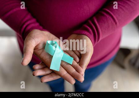 Sezione centrale della donna di metà adulto afroamericana con nastro blu di consapevolezza del cancro della prostata