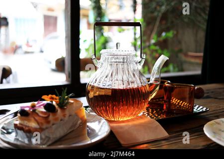 set di tè pomeridiano composto da una pentola di tè e un pezzo di torta in un caffè Foto Stock