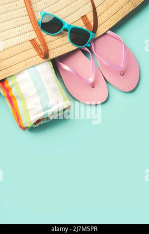 Vacanza estiva Concept.Top vista della borsa da spiaggia con infradito, telo da spiaggia, occhiali da sole e spazio per il testo su sfondo blu Foto Stock