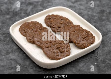 Cioccolato speciale con particelle di nocciola. Cioccolato con nocciole su sfondo scuro. Primo piano Foto Stock