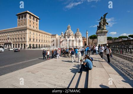 Turisti in piazza Venezia, sullo sfondo le chiese di Santa Maria di Loreto e SS. Nome di Maria e colonna di Traiano, Roma, Lazio, Italia Foto Stock