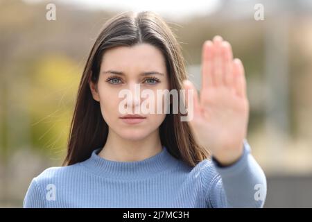 Vista frontale ritratto di un teen arrabbiato gesturing stop in un parco Foto Stock