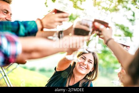 Brindisi mani con vino rosso - persone che si divertono a pic nic Winetasting - giovani amici che godono il tempo di raccolta insieme al vigneto cou fattoria Foto Stock