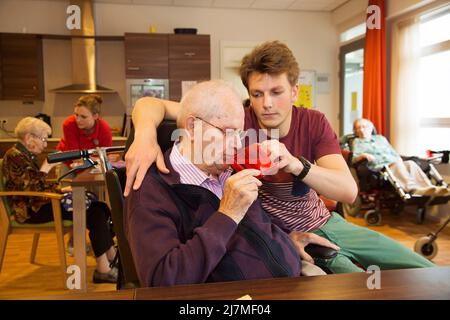 Paesi Bassi, Gendt - nipote sta aiutando suo nonno con il suo caffè. Si trovano in una casa di cura nella sezione chiusa per anziani degentati. Foto Stock