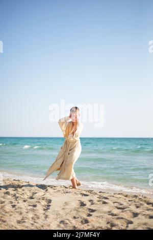 Pratica sulla spiaggia. Un ragazzo in un kimono sulla riva del mare. Balli. Esercizi respiratori orientali. Foto Stock